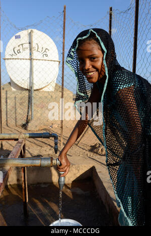 DJIBOUTI , Obock, refugee camp Markazi for yemeni war refugees, girl fetch water from tap, slogan water is life written on tank / DSCHIBUTI, Obock, Fluechtlingslager Markazi fuer jemenitische Fluechtlinge, Wasserstelle Stock Photo