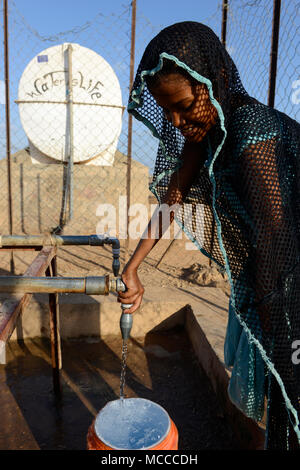 DJIBOUTI , Obock, refugee camp Markazi for yemeni war refugees, girl fetch water from tap, slogan water is life written on tank / DSCHIBUTI, Obock, Fluechtlingslager Markazi fuer jemenitische Fluechtlinge, Wasserstelle Stock Photo