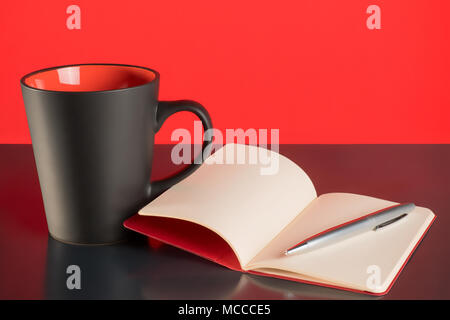 Coffee cup, open notebook and pen on black table and red background Stock Photo