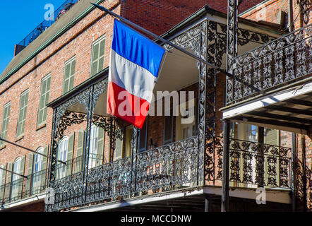 French flag hanging from cast iron balcony on a building in the French Quarter, New Orleans, Louisisana, United States. Stock Photo