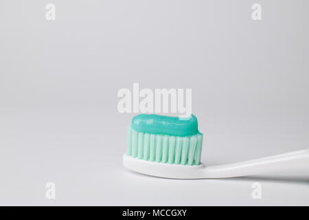 Green toothpaste on a toothbrush on white background - closeup Stock Photo