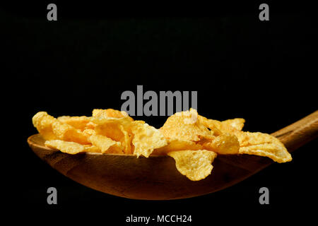 Wooden spoon with corn flakes on the black background Stock Photo