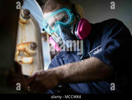 180212-N-NG033-1117 ARABIAN GULF (Feb. 12, 2018) Boatswain’s Mate Seaman Tyler Aytes strips paint from a bulkhead aboard the aircraft carrier USS Theodore Roosevelt (CVN 71). Theodore Roosevelt and its carrier strike group are deployed to the U.S. 5th Fleet area of operations in support of maritime security operations to reassure allies and partners and preserve the freedom of navigation and the free flow of commerce in the region. (U.S. Navy photo by Mass Communication Specialist Seaman Michael Hogan/Released) Stock Photo