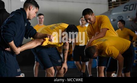 180212-N-NG033-1213 ARABIAN GULF (Feb. 12, 2018) Sailors conduct hand-to-hand combat training in the hangar bay of the aircraft carrier USS Theodore Roosevelt (CVN 71). Theodore Roosevelt and its carrier strike group are deployed to the U.S. 5th Fleet area of operations in support of maritime security operations to reassure allies and partners and preserve the freedom of navigation and the free flow of commerce in the region. (U.S. Navy photo by Mass Communication Specialist Seaman Michael Hogan/Released) Stock Photo