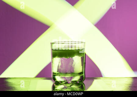 Liquid with ice in a glass on a reflective surface on a reddish background 2018 Stock Photo