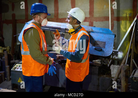 Machine Operators Wrapped up in Discussion Stock Photo