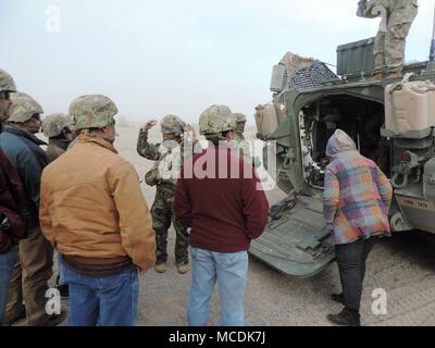 Maj. John Rhodes, executive officer for 2nd Squadron, 3rd Cavalry Regiment, III Corps, provides an overview of the Stryker combat vehicle during a sandstorm at the National Training Center in Fort Irwin, Calif., Feb. 18, 2018. The Killeen and Harker Heights Chambers of Commerce NTC visit is designed to strengthen relationships between civic leaders in the surrounding Fort Hood community and service members assigned to Fort Hood, Texas. (US Army photo by Maj. Anthony Clas, 7th Mobile Public Affairs Detachment) Stock Photo