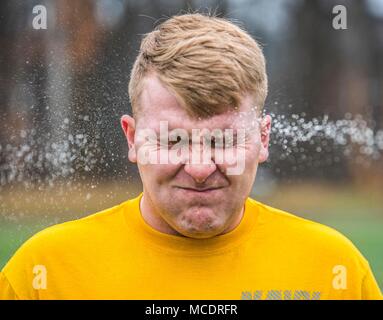 Information System Technician Seaman Phelan Payne is sprayed in the face with OC spray (oleoresin capsicum) while completing the OC course Feb. 23 at Naval Support Activity Bethesda. After being sprayed, students go through multiple physical challenges to complete the capstone event for the Auxiliary Security Forces Academy. (U.S. Navy photo by Mass Communication Specialist 2nd Class William Phillips/Released) Stock Photo