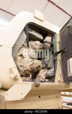 Mississippi Army National Guard Capt. Matthew D. McCann, an aviation officer assigned to Headquarters Company, 155th Armored Brigade Combat Team, braces himself before exiting a high mobility multi-purpose wheeled vehicle, or HMMWV, as part of an HMMWV Egress Assistance Training exercise at the Camp Shelby Joint Forces Training Center, just South of Hattiesburg, Miss., Feb. 24, 2018. HEAT exercises train Soldiers on proper vehicle exiting procedures in the event of a rollover. (U.S. Army National Guard photo by Spc. Jovi Prevot) Stock Photo