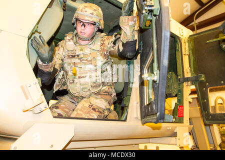 Mississippi Army National Guard Private 1st Class Elizabeth Smith, an intelligence analyst assigned to Headquarters Company, 155th Armored Brigade Combat Team, exits a high mobility multi-purpose wheeled vehicle, or HMMWV, as part of an HMMWV Egress Assistance Training exercise at the Camp Shelby Joint Forces Training Center, just South of Hattiesburg, Miss., Feb. 24, 2018. HEAT exercises train Soldiers on proper vehicle exiting procedures in the event of a rollover. (U.S. Army National Guard photo by Spc. Jovi Prevot) Stock Photo