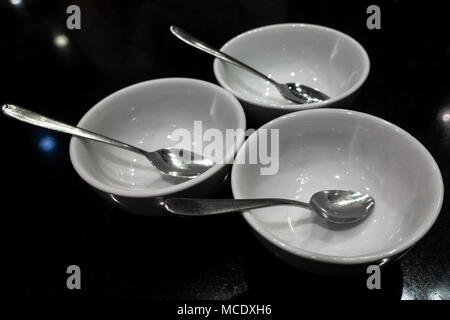 Blank white dishes with spoon on the black table, Philippines Stock Photo