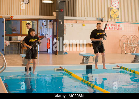 U.S. Army Spc. Jacqueline Delgado (left), assigned to the Chièvres Military Police at U.S. Army Garrison Benelux, and Spc. Jesse Watkins (right), assigned to the Schinnen Provost Marshal Office at USAG Benelux, compete for the garrison’s Best Warrior Competition in the swimming pool at the Supreme Headquarters Allied Powers Europe, Belgium, Feb. 21, 2018. (U.S. Army photo by Visual Information Specialist Pierre-Etienne Courtejoie) Stock Photo