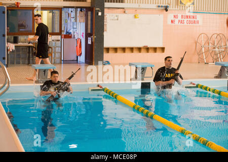 U.S. Army Spc. Jacqueline Delgado (left), assigned to the Chièvres Military Police at U.S. Army Garrison Benelux, and Spc. Jesse Watkins (right), assigned to the Schinnen Provost Marshal Office at USAG Benelux, compete for the garrison’s Best Warrior Competition in the swimming pool at the Supreme Headquarters Allied Powers Europe, Belgium, Feb. 21, 2018. (U.S. Army photo by Visual Information Specialist Pierre-Etienne Courtejoie) Stock Photo