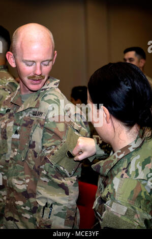 CAMP ARIFJAN, Kuwait – Spc. Meghan O’Connell a member of the Massachusetts National Guard’s 151st Regional Support Group from Scituate, Mass., removes the U.S. Army Central Command patch from Sgt. Matthew Moore, with the Kansas National Guard’s 635th Regional Support Command, Kansas February 28. The two were participating in a change of authority ceremony where the 151st replaced the 635th, beginning only the second ever rotation of National Guard Soldiers to take on the support mission for U.S. Army Central, which commands the U.S.  Army’s land forces in the Middle East. (U.S. Army photo by S Stock Photo