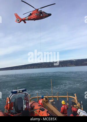 Coast Guard Cutter Naushon (WPB 1311) and crew conduct hoist training with an Air Station Kodiak MH-65 Dolphin helicopter crew in Kachemak Bay near Homer, Alaska, Feb. 21, 2018. Hoist training ensures both the boat crew and aircrew are proficient in these skills when search and rescue calls arrive. U.S. Coast Guard photo. Stock Photo