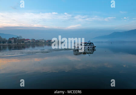 Small wooden boat floating the calm waters on lake Pamvotis and transfer passengers to a very small island inside the lake. Greece. Stock Photo
