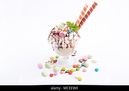 Illuminating ice cream in a glass bowl with colored ornaments and waffle sticks. Ice cream on white background. Isolated. Stock Photo