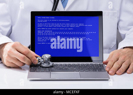 Close-up Of A Doctor's Hand Examining Laptop With Stethoscope Stock Photo