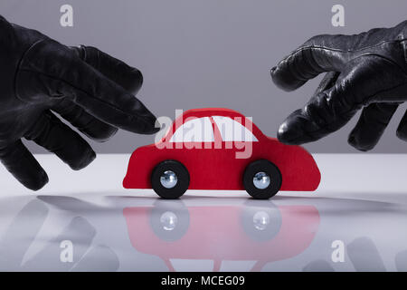 Close-up Of A Thief's Hand Wearing Gloves Stealing Red Car Stock Photo