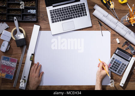 Elevated View Of Architecture's Hand Drawing Blueprint With Pencil On Wooden Desk Stock Photo