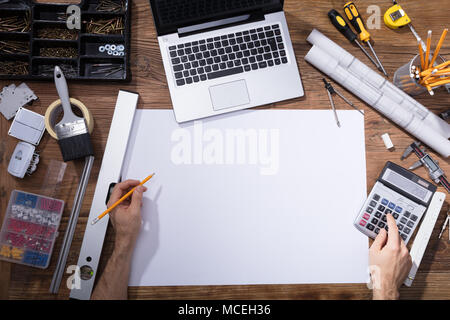 Elevated View Of Architecture's Hand Drawing Blueprint With Pencil On Wooden Desk Stock Photo
