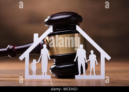 White Family Paper Cut Out In Front Of Judge Gavel On The Wooden Desk Stock Photo