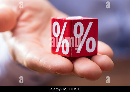 Close-up Of Hand Holding Red Wooden Block With White Percentage Symbol On It Stock Photo