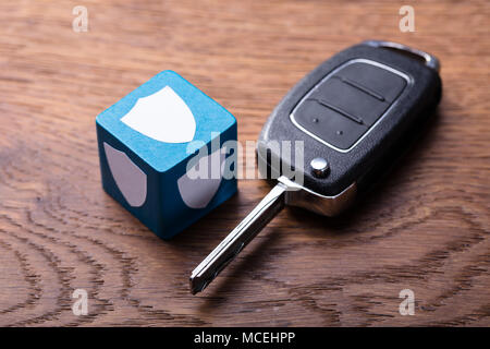 Elevated View Of Shield Shape On Block With Car Key On Wooden Table Stock Photo
