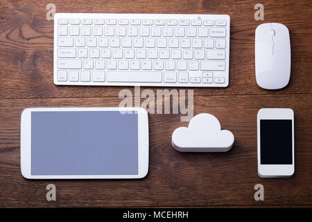 White Cloud Block With Digital Tablet, Mobile, Keyboard And Mouse On The Wooden Table Stock Photo