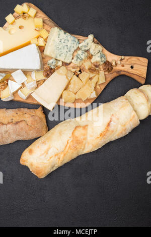 various types of cheese and bread on wooden board Stock Photo