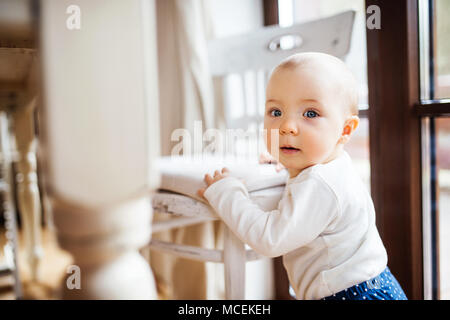 A toddler girl standing at the table at home. Stock Photo