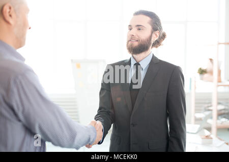 Two businessmen shaking hands at office. They are concluding a deal Stock Photo
