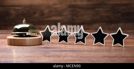 Black Five Stars Shape Arranged In Row With Service Bell On Wooden Table Stock Photo