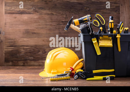 Close-up Of Safety Helmet With Tools In The Black Container On The Wooden Table Stock Photo