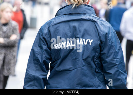A female Royal Navy sailor wearing uniform with blue logo from rear view, UK Stock Photo