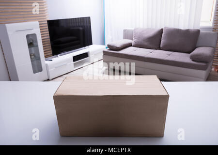 Close-up Of Cardboard Box On White Desk In Living Room Stock Photo