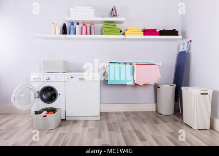 Basket Full Of Dirty Clothes In Front Of Washing Machine At Laundry Room Stock Photo