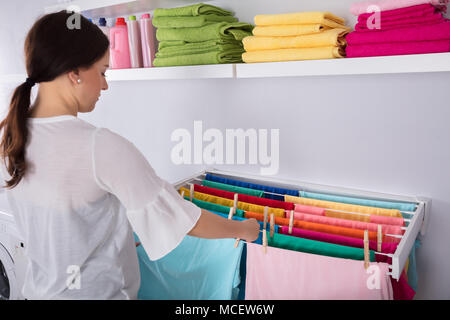 Side View Of A Young Woman Hanging Wet Clothes On In Laundry Room Stock Photo
