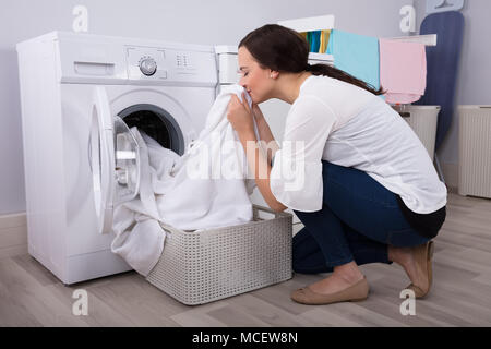 Close-up Of A Young Woman Smelling White Cloth After Washing In Washing Machine Stock Photo