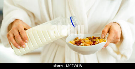 Closeup on woman pouring milk into plate with oatmeal Stock Photo
