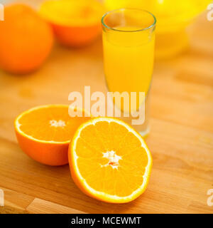 Closeup on glass of orange juice and oranges on cutting board Stock Photo