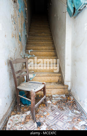 Wooden chair with ruined wall and staircase of old building Stock Photo