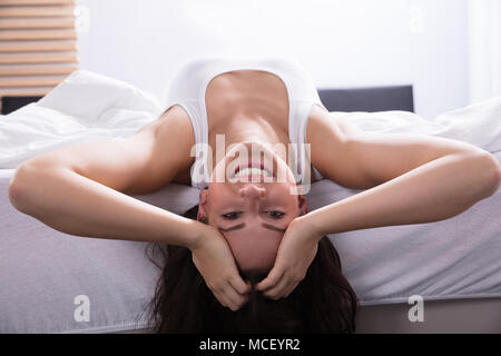 Close-up Of A Smiling Young Woman Lying On Bed Stock Photo