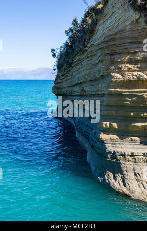 Crystal clear blue water and beautiful segmented sea rock near the famous Tunnel of Love, or as it is originally called Canal d'Amour near Sidari, Cor Stock Photo