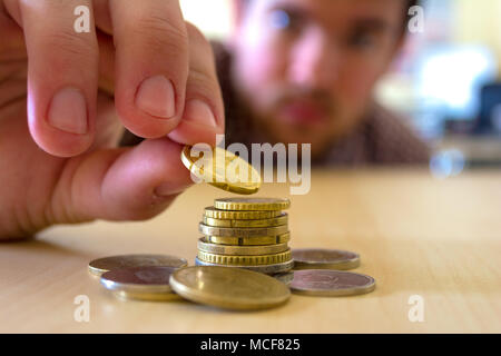 The coins are stacked. The men's hands are gently putting coin on top of the stack. Concept of saving money and growing financially. The new currency  Stock Photo