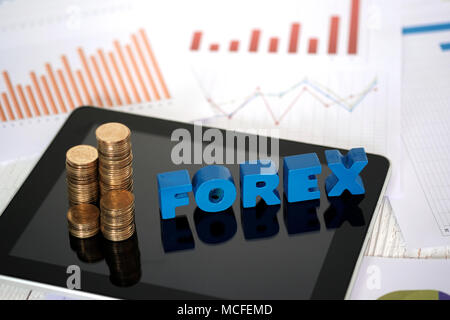 FOREX text and stack of coin with tablet computer and financial graph chart on paper, business planning vision and finance analysis concept idea. Stock Photo