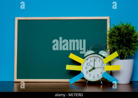 Adhesive notes paper sticky and vintage alarm clock and blank green chalkboard on table with copy space for add text notice something, list memo Stock Photo