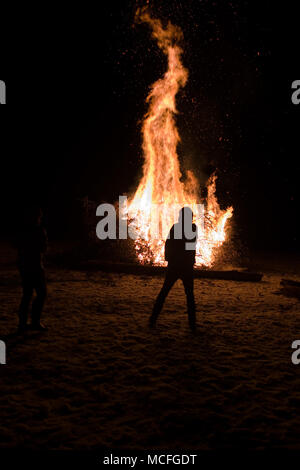 person standing in the snow in front of a large bonfire on a winter’s night in the Cevennnes, France Stock Photo