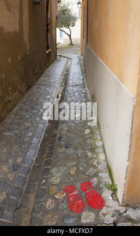 Red painted footprints at the end of a narrow alley, Céret, Pyrénées-Orientales, Occitaine Region, southern France. Stock Photo