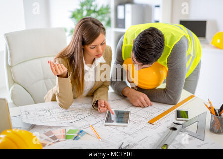 Successful young architects checking the architectural plans on tablet in the office, discussing and planning what to change to be better. Stock Photo